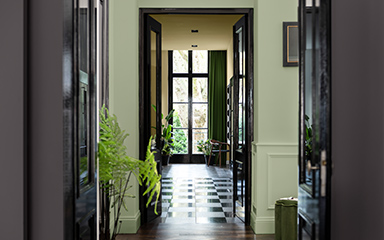 Looking through a doorway into a hallway, with walls painted in different shades of green