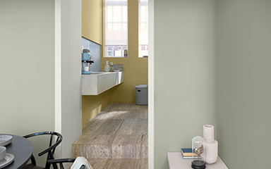 Looking through a doorway into a kitchen, with walls painted in pale grey and straw yellow