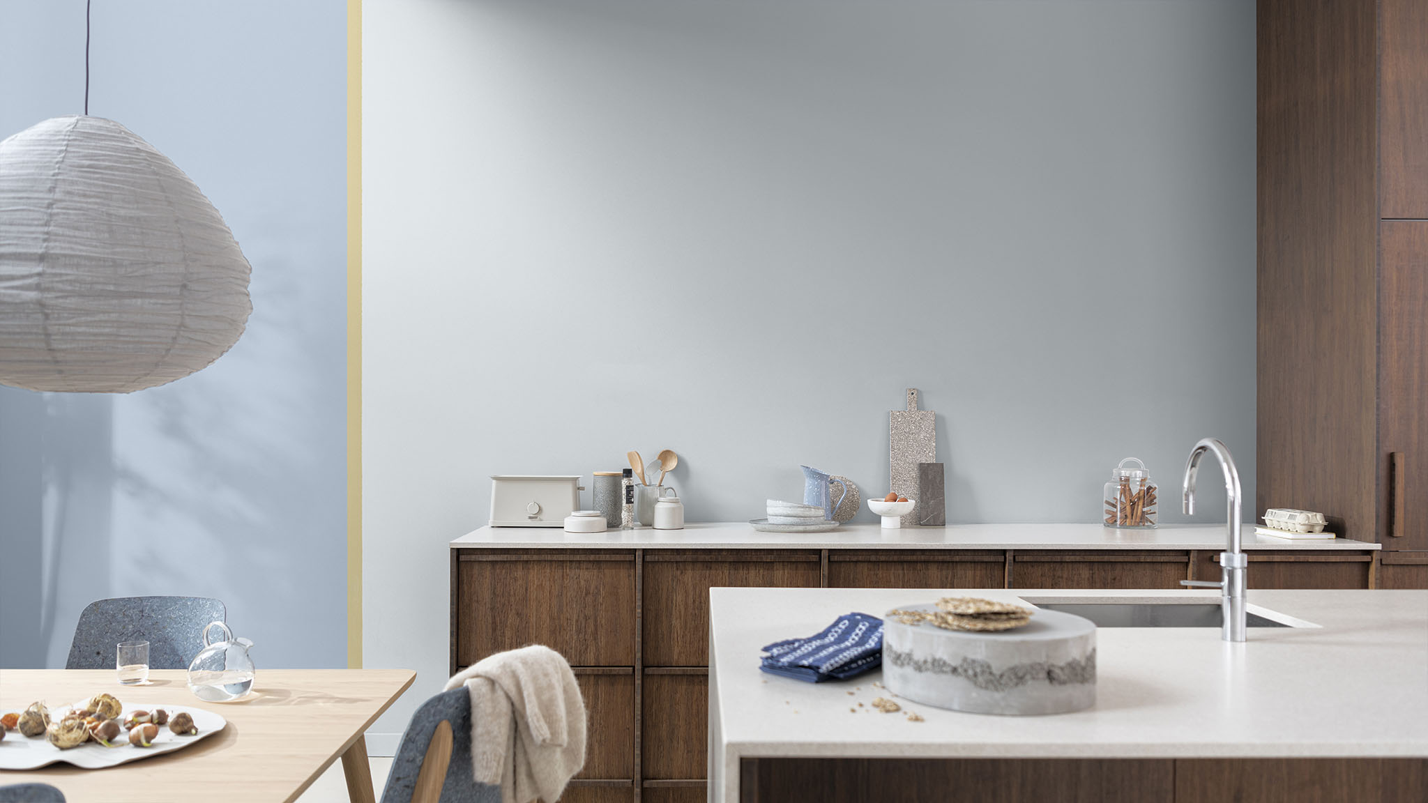 A kitchen area with white topped wooden units defined with a painted square of light grey blue. 
