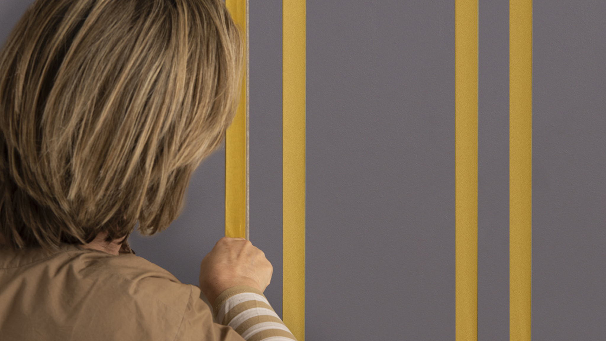 Someone applying masking tape to create vertical lines