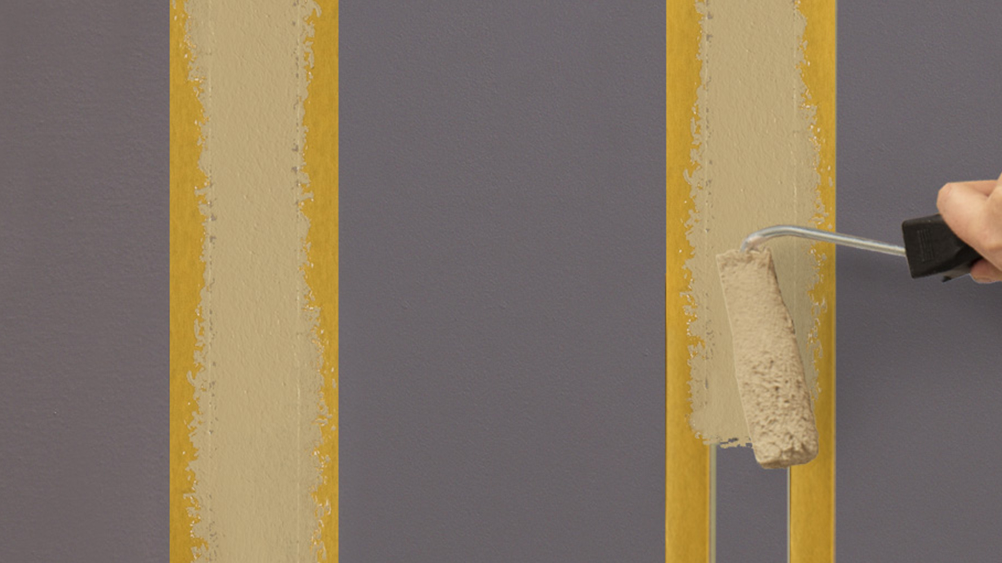 Someone applying paint with a small roller between two lengths of masking tape